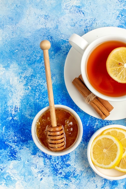 Draufsichttasse teehonig in schüsselzitronenscheiben auf blauem tisch