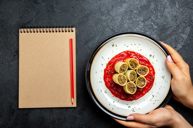 Draufsichtteig mit Fleischscheibenscheiben mit Tomatensauce auf grauem Schreibtisch