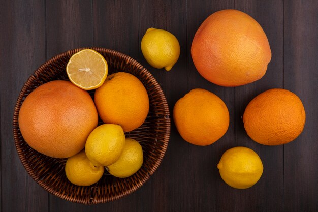Draufsichtzitronen mit Orangen und Grapefruits mit Korb auf hölzernem Hintergrund