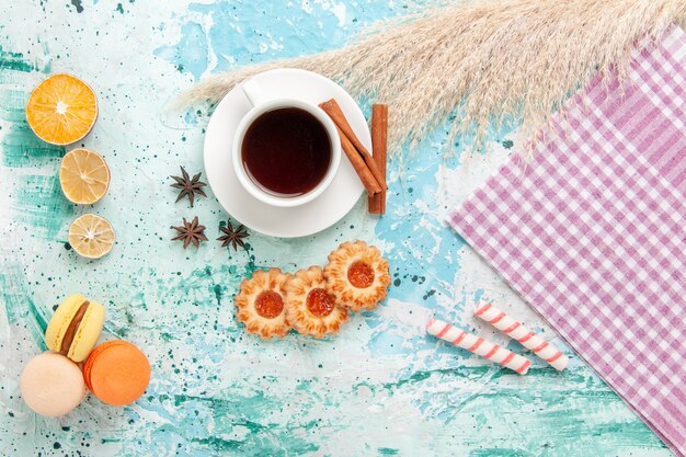 Draufsichtzuckerplätzchen mit Tasse Tee und Macarons auf dem blauen Hintergrund