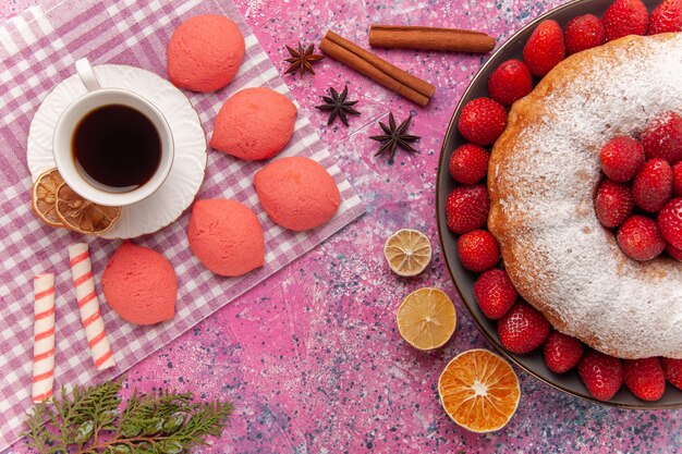 Draufsichtzuckerpulver-Erdbeerkuchen mit Tee und Kuchen auf rosa