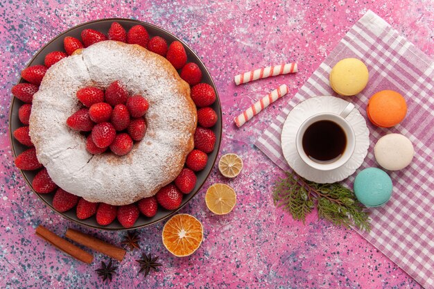 Draufsichtzuckerpulverkuchen mit französischen Macarons und Tee auf Rosa