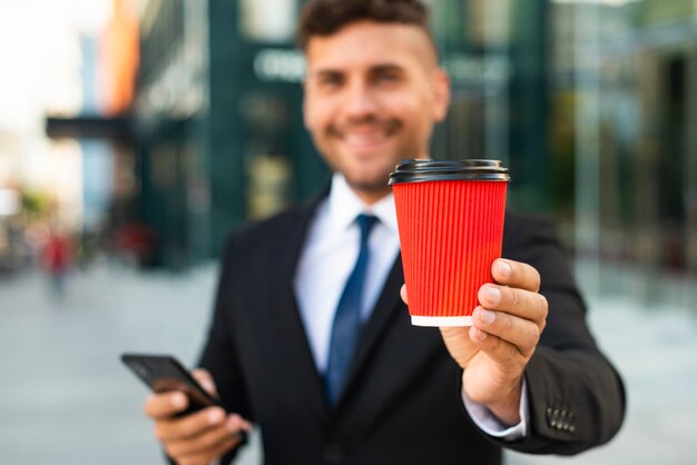 Draußen Geschäftsmann, der eine rote Tasse Kaffee hält