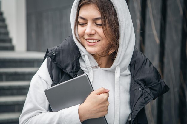 Draußen steht eine junge Studentin mit einem digitalen Tablet in der Hand