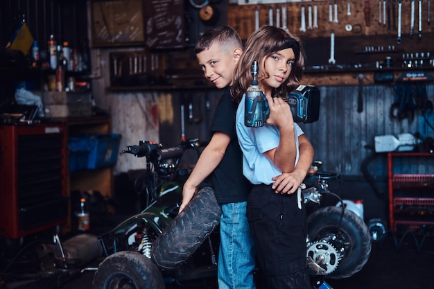 Dreamteam in Aktion - zwei Kinder amüsieren sich, während sie in einer Autowerkstatt für Fotografen posieren.