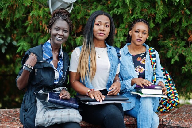 Drei afrikanische Studentinnen posierten mit Rucksäcken und Schulsachen auf dem Hof der Universität