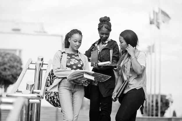 Drei afrikanische Studentinnen posierten mit Rucksäcken und Schulsachen auf dem Hof der Universität
