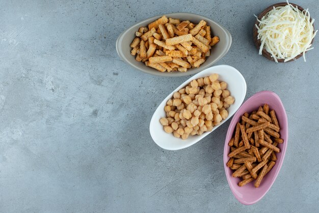 Drei bunte Teller mit leckeren Snacks mit Holzschale voller Käse. Foto in hoher Qualität