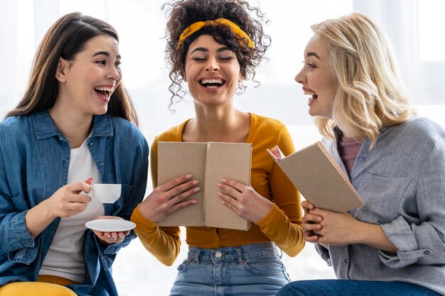 Drei Frauen lachen zusammen mit Buch