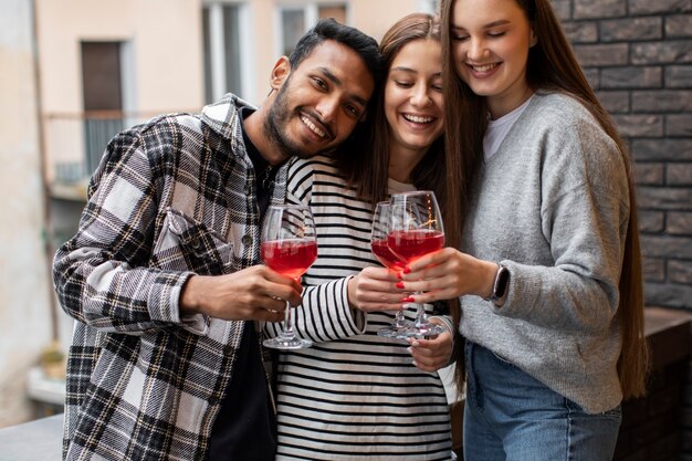 Drei Freunde bei einem Treffen, die Getränke halten und lächeln