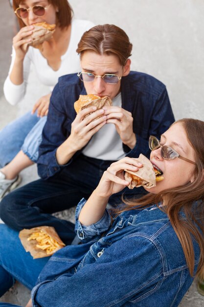 Drei Freunde essen Burger im Freien