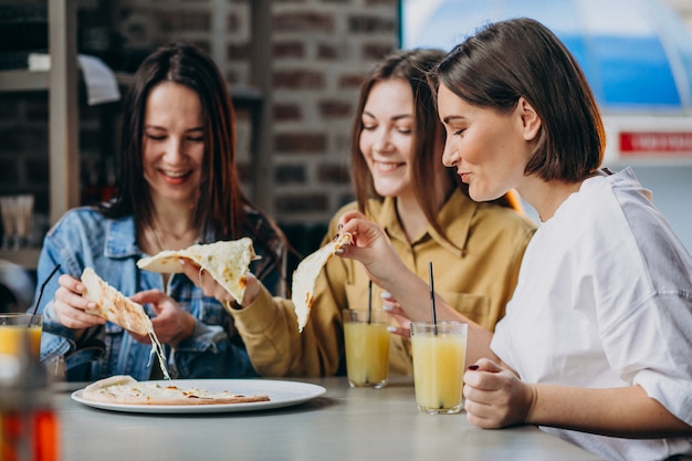 Drei Freundinnen, die Pizza an einer Bar essen