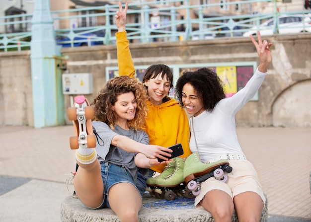 Kostenloses Foto drei freundinnen mit rollschuhen machen ein selfie im freien