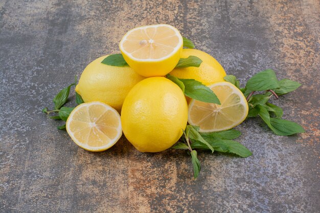 Drei ganze frische Zitronen mit Scheibe auf Marmorfläche