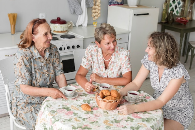 Drei Generationsfrauen, die etwas während des Frühstücks sprechen