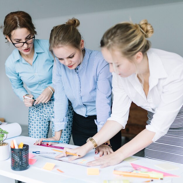 Drei Geschäftsfrauen, die Geschäftsdiagramm auf Schreibtisch im Büro vorbereiten