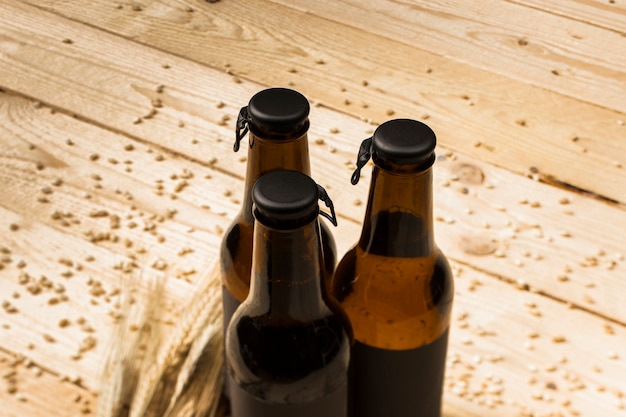Drei geschlossene Bierflaschen und Ähren auf Woodgrain