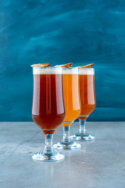 Drei Gläser helles Bier mit Fisch auf grauem Hintergrund. Foto in hoher Qualität