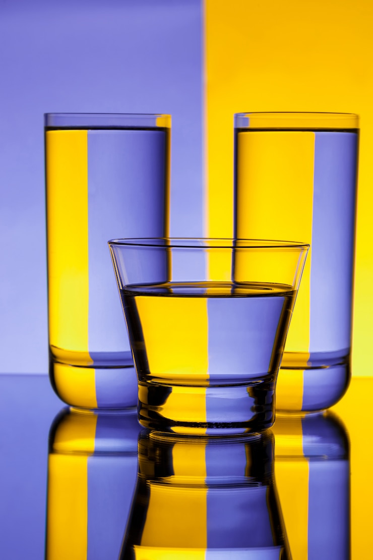 Kostenlose Foto drei gläser mit wasser über lila und gelber wand