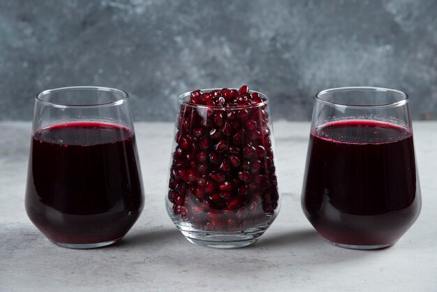 Drei Glasbecher Granatapfelsaft auf Marmor.