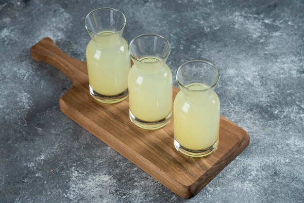 Drei Glaskrüge frische Limonade auf Holzbrett