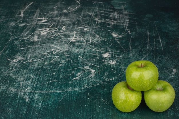 Kostenloses Foto drei grüne äpfel auf marmoroberfläche.