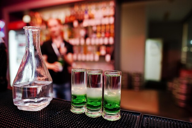 Drei grüne mexikanische Coctail-Getränke und Karaffen-Hintergrund-Barkeeper an der Bar
