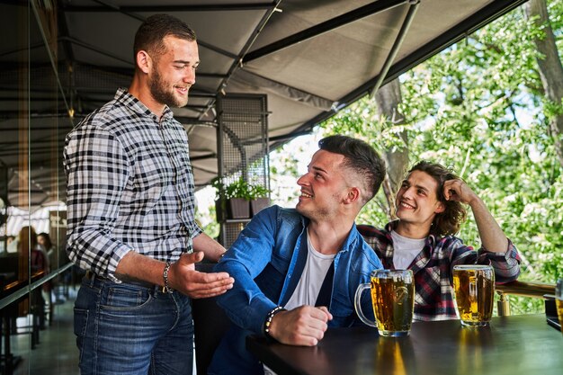 Drei gutaussehende Männer treffen sich zum Biertrinken in einer Kneipe.