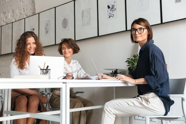 Drei hübsche Frauen sitzen und arbeiten am Tisch