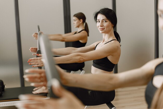 Drei junge Frauen trainieren im Fitnessstudio. Frauen, die schwarze Sportkleidung tragen. Kaukasische Mädchen trainieren mit Ausrüstung.