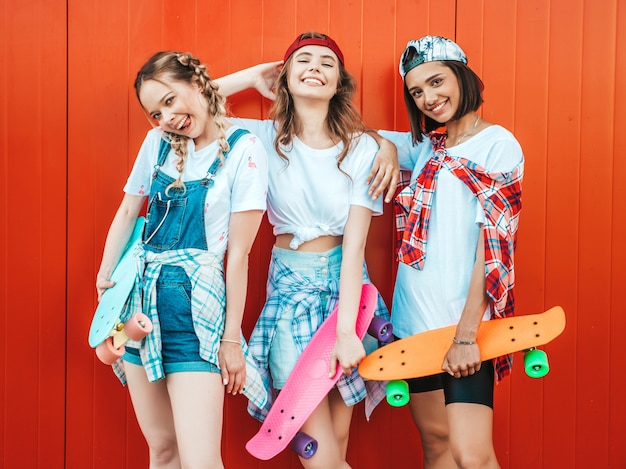 Kostenloses Foto drei junge lächelnde schöne mädchen mit bunten penny skateboards.