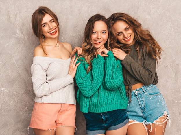 Drei junge schöne lächelnde herrliche mädchen in der modischen sommerkleidung. sexy sorglose frauenaufstellung. positive models, die spaß an einer runden sonnenbrille haben