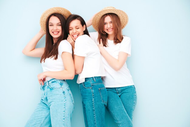 Drei junge schöne lächelnde Hipster-Frau in trendigen weißen T-Shirts und Jeans im gleichen Sommer