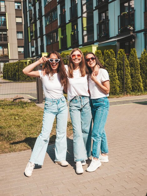 Drei junge schöne lächelnde Hipster-Frauen im trendigen Sommer gleiche Kleidung Sexy sorglose Frauen posieren auf der Straße HintergrundPositive Models, die Spaß mit Sonnenbrillen habenUmarmung Fröhlich und glücklich