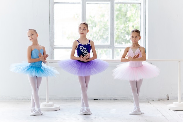 Kostenloses Foto drei kleine ballettmädchen im tutu und posieren zusammen