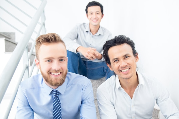 Drei lächelnde Geschäftsleute sitzen auf Treppen