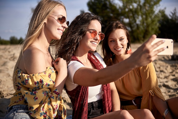 Drei Mädchen machen ein Selfie am Strand