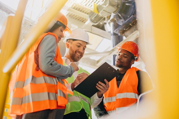 Drei Personen diskutieren in einer Fabrik über einen Plan