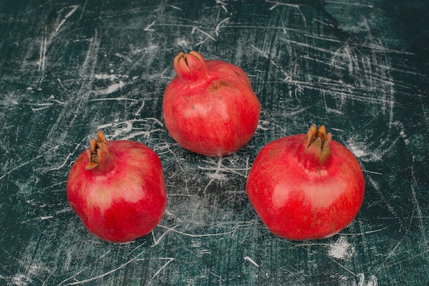 Kostenloses Foto drei reife granatäpfel auf marmortisch.