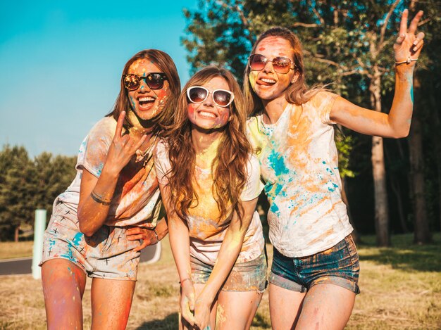 Drei schöne lächelnde Mädchen, die auf Holi Party aufwerfen