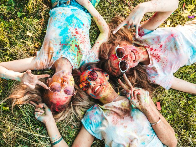 Drei schöne lächelnde Mädchen, die auf Holi Party aufwerfen