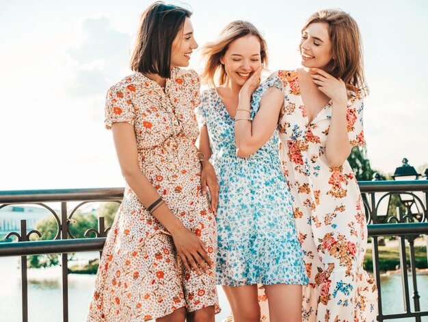 Drei schöne lächelnde Mädchen im trendigen Sommer-Sommerkleid, das auf der Straße aufwirft