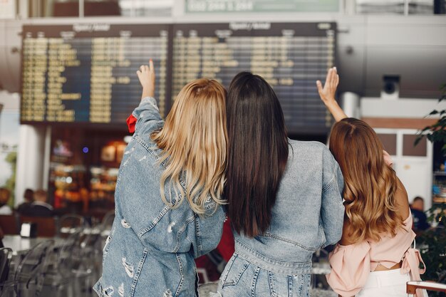 Drei schöne Mädchen, die den Flughafen bereitstehen