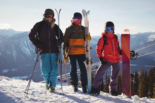 Drei Skifahrer mit Himmel, der auf Schneelandschaft steht