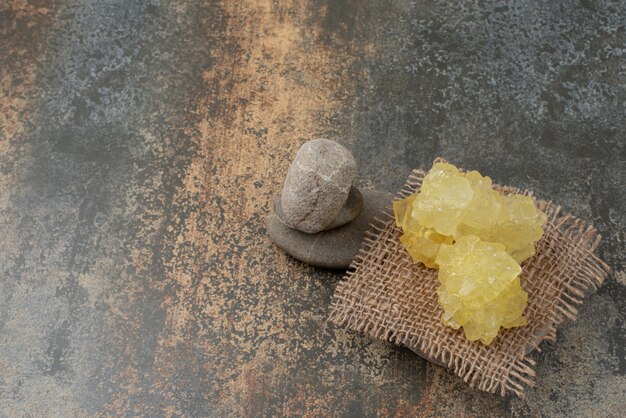 Drei Steine mit Scheiben von süßem gelbem Zucker auf Marmoroberfläche.