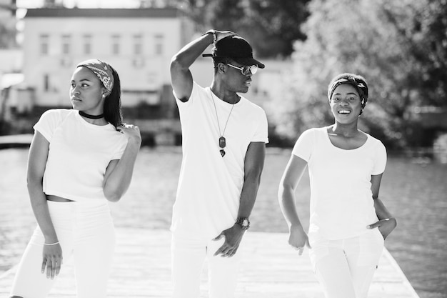 Drei stilvolle afroamerikanische Freunde tragen weiße Kleidung Straßenmode junger schwarzer Menschen Schwarzer Mann mit zwei afrikanischen Mädchen posiert