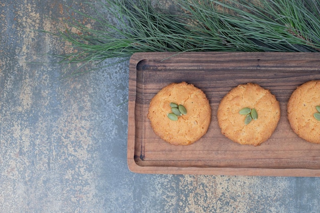 Kostenloses Foto drei süße kekse mit kürbiskernen auf holzbrett.