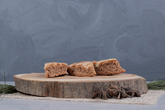 Drei süße Scheiben Kuchen mit Sternanis auf Holzteller. Hochwertiges Foto