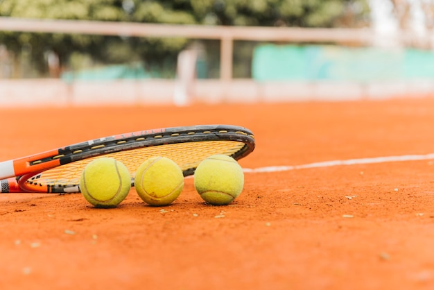 Drei Tennisbälle mit Schläger