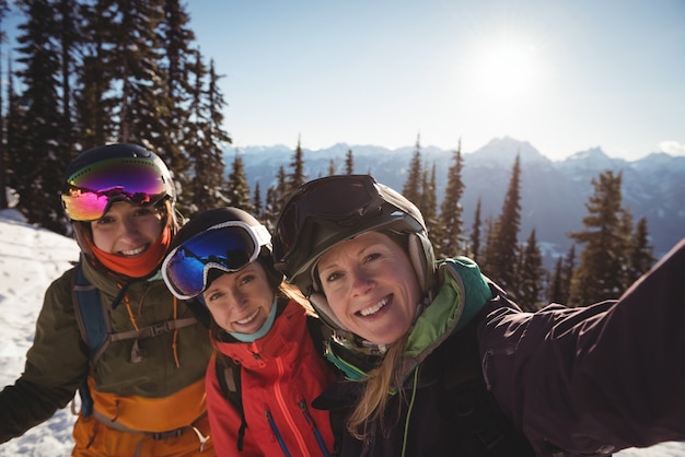 Drei weibliche Skifahrer, die zusammen auf schneebedecktem Berg stehen